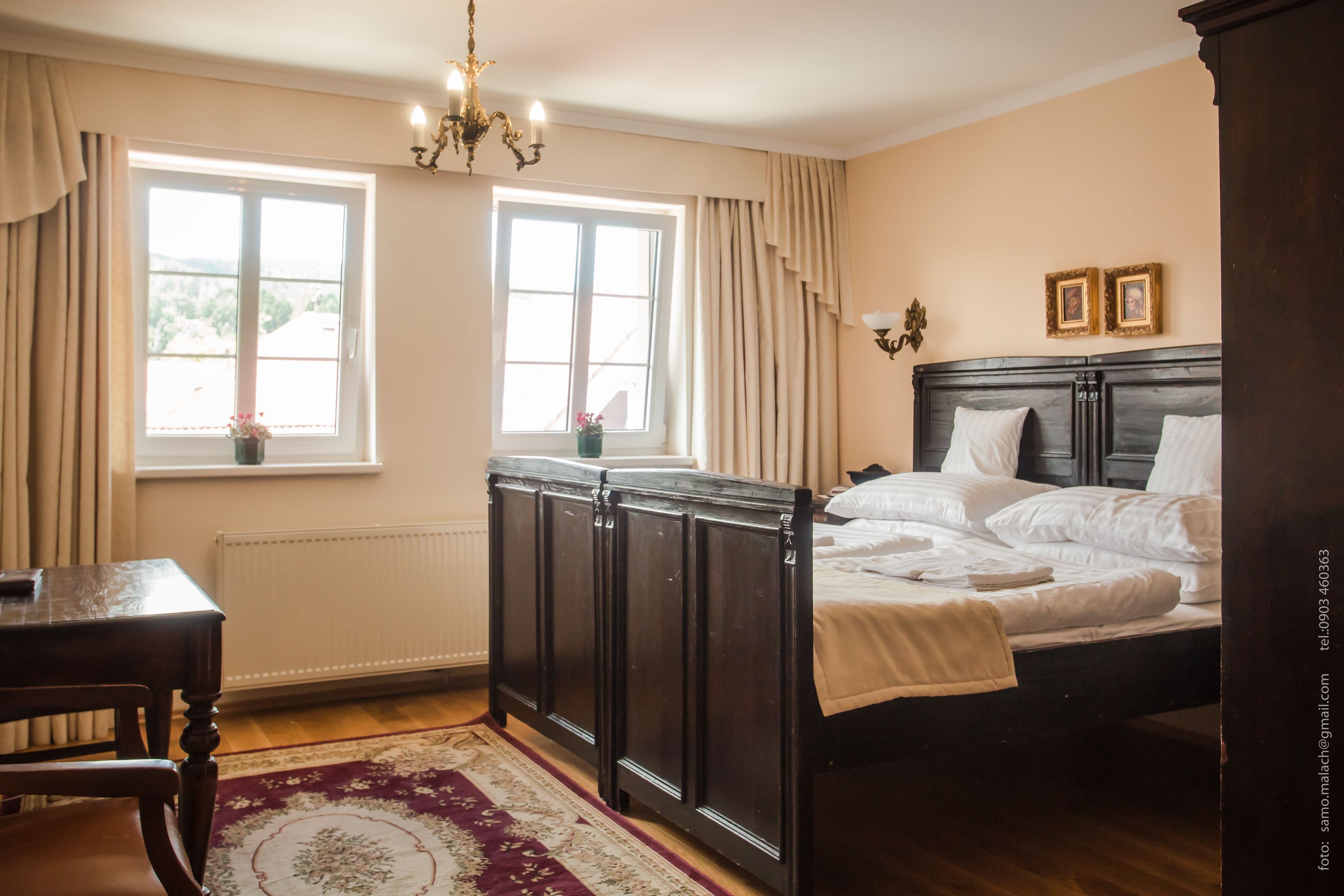 Une chambre à coucher comprenant un lit, une commode, une table de chevet, une fenêtre avec des rideaux et un lustre.