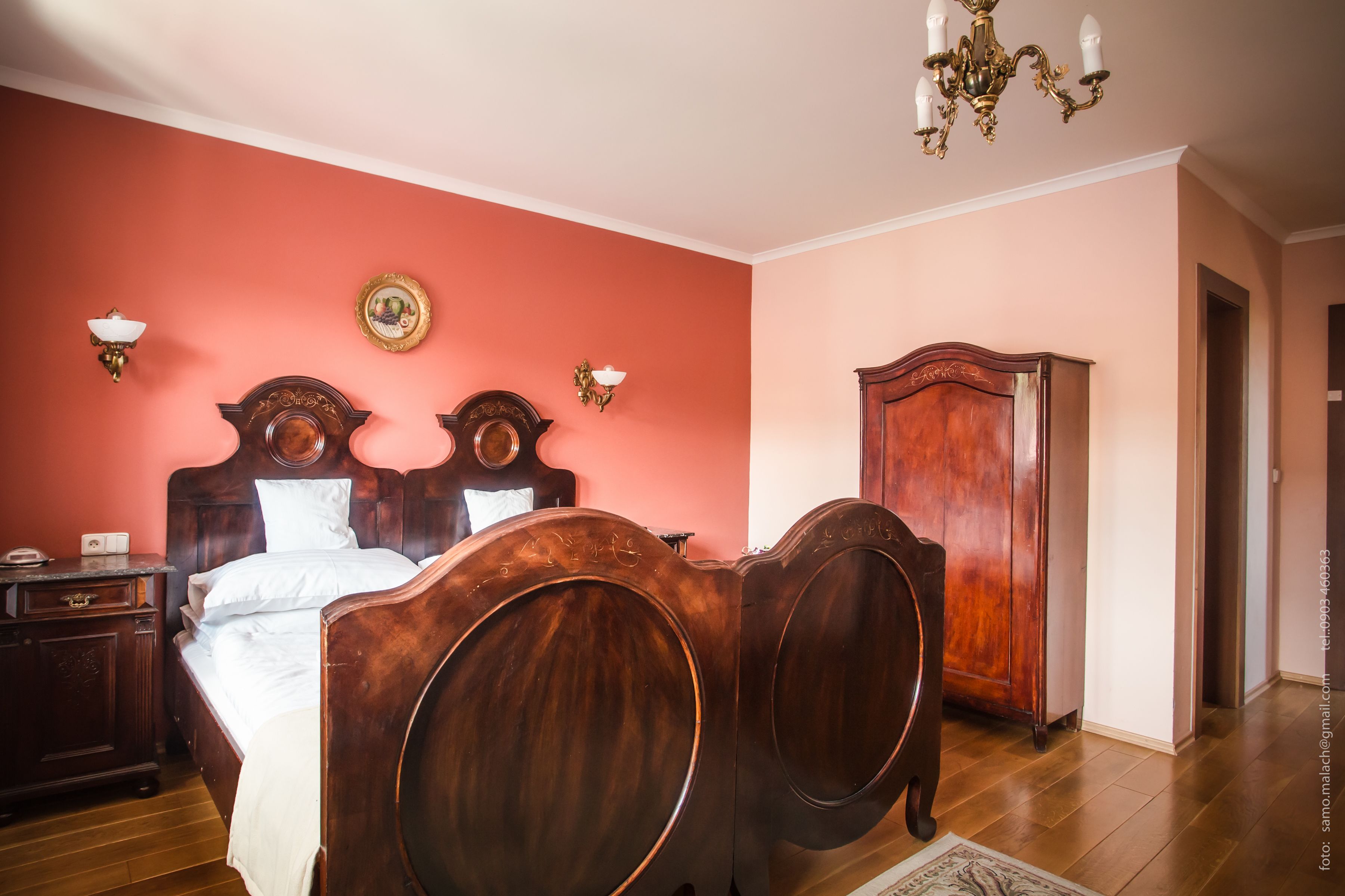 Un dormitorio con una cama doble, un armario de madera y una araña.