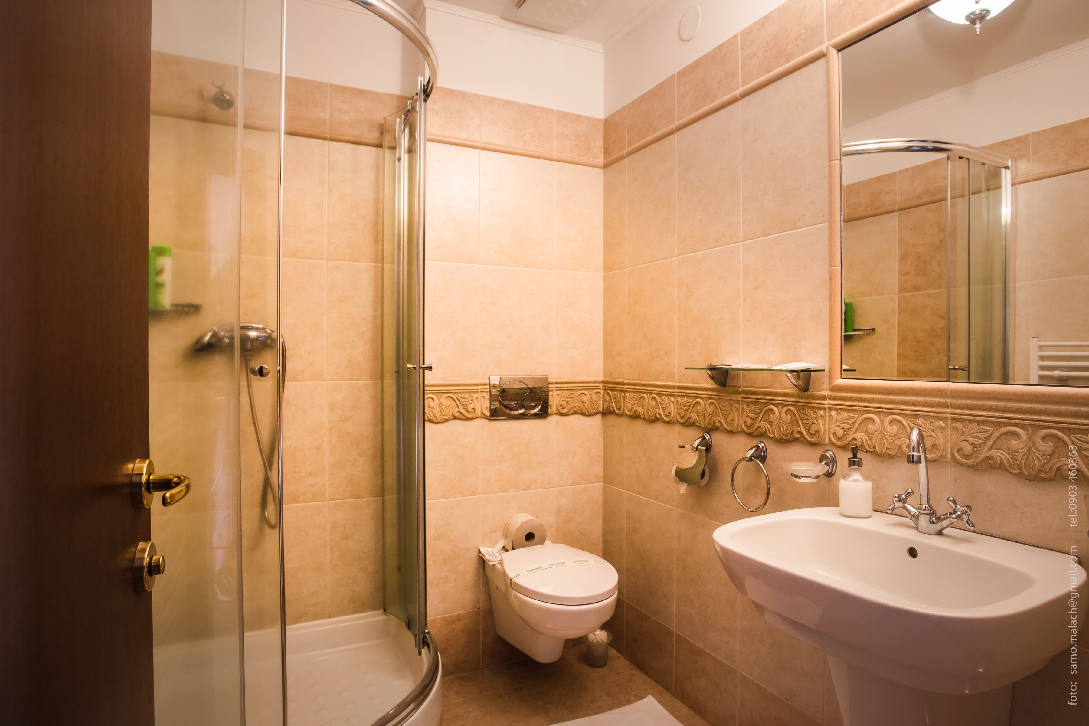 A bathroom with a glass shower enclosure, a toilet, and a sink with a mirror above it.