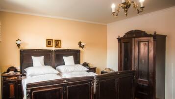 A bedroom with a large wooden bed, two bedside tables, a wardrobe, and a chandelier.