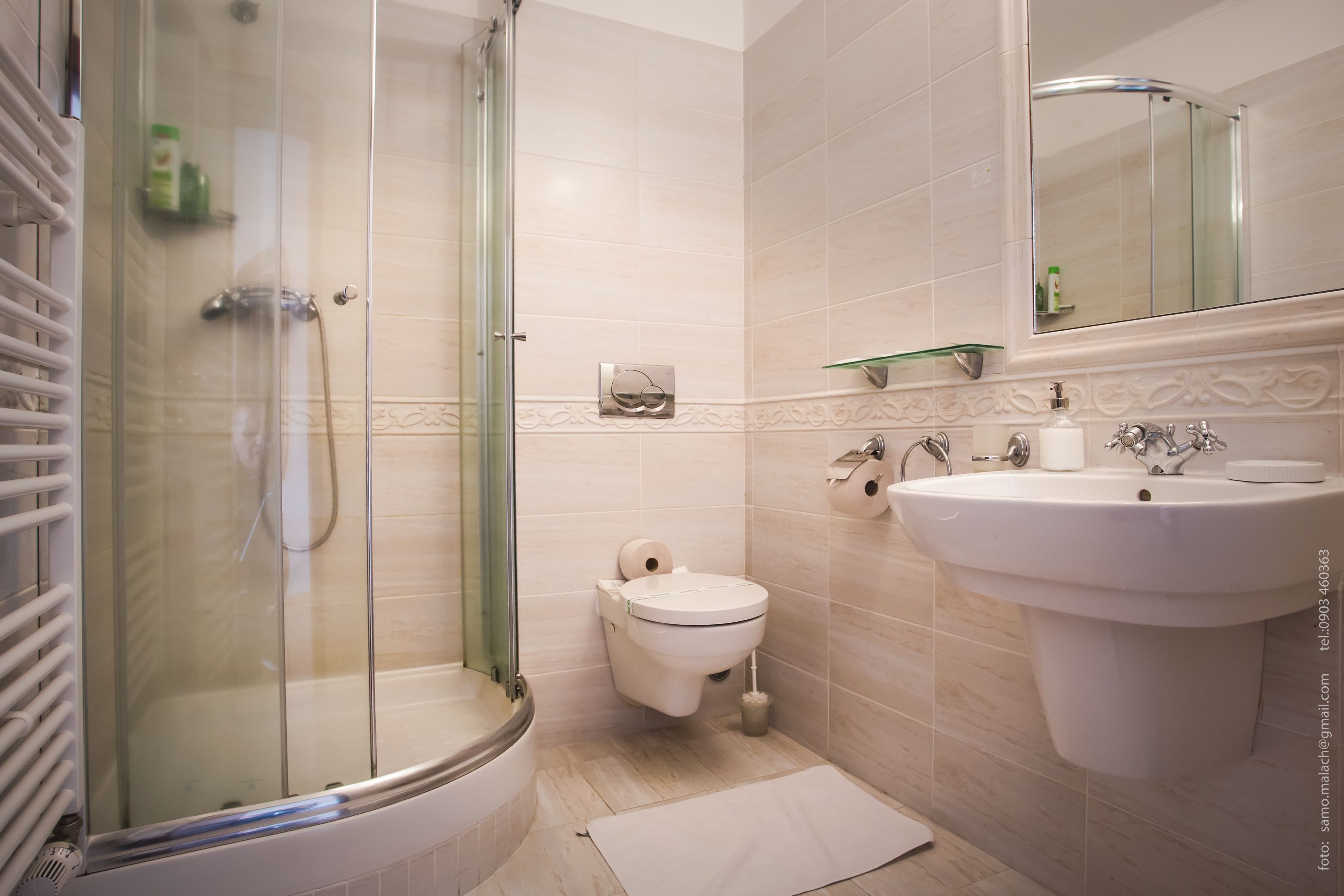 A bathroom with a glass-enclosed shower, a toilet, and a sink with a mirror above it.