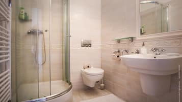 A bathroom with a glass-enclosed shower, a toilet, and a sink with a mirror above it.