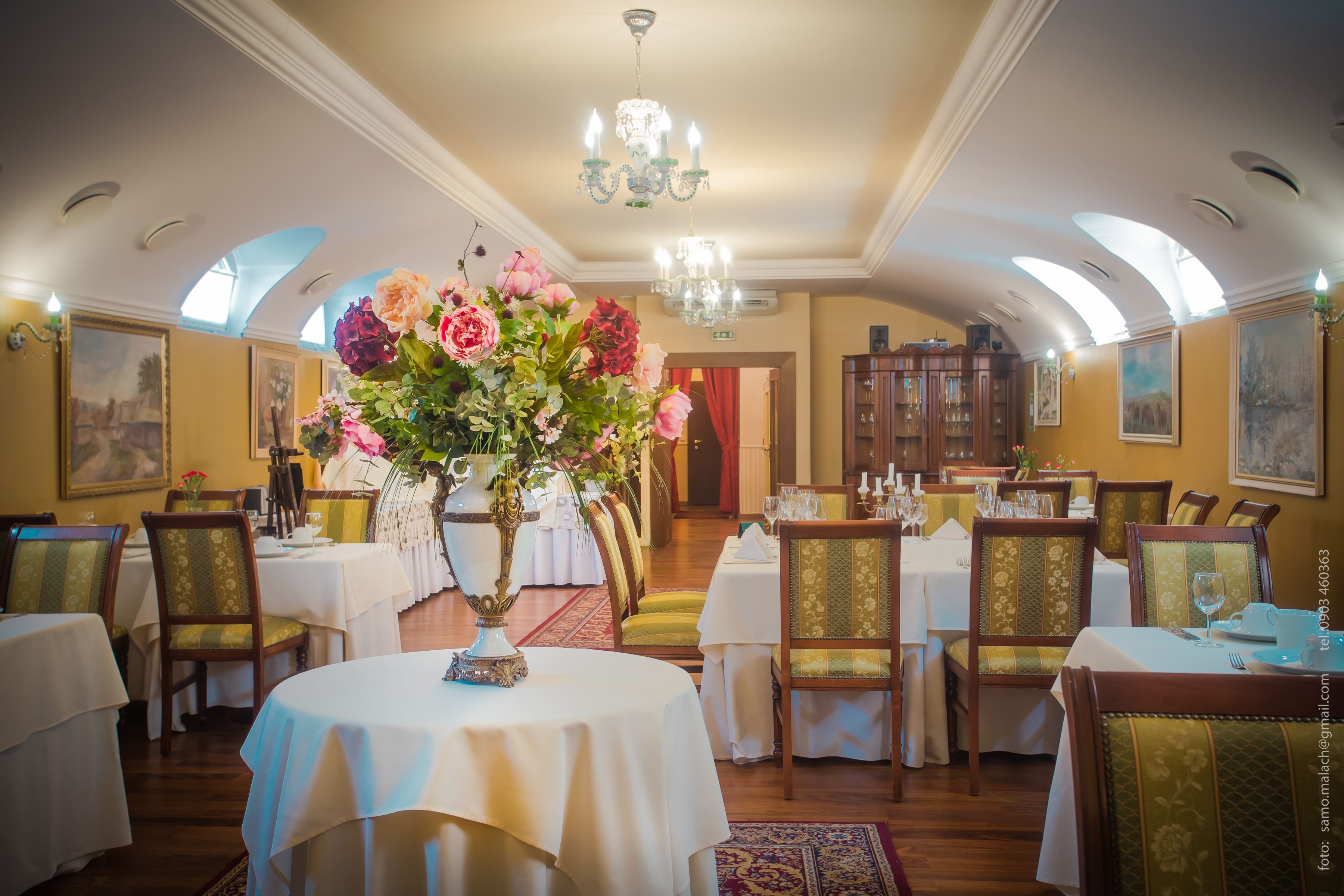 A dining area with round tables, chairs, and a chandelier.
