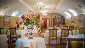 A dining area with round tables, chairs, and a chandelier.