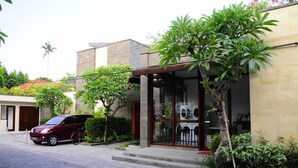 A modern building with a carport, a visible laundry service, and a small garden area. - Puri Mesari Suites (Denpasar)