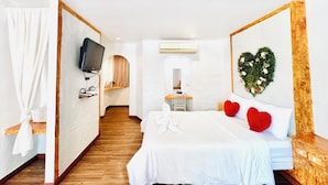 Een hotelkamer met een bed, een televisie, een spiegel, een bureau en een hartvormige decoratie aan de muur.