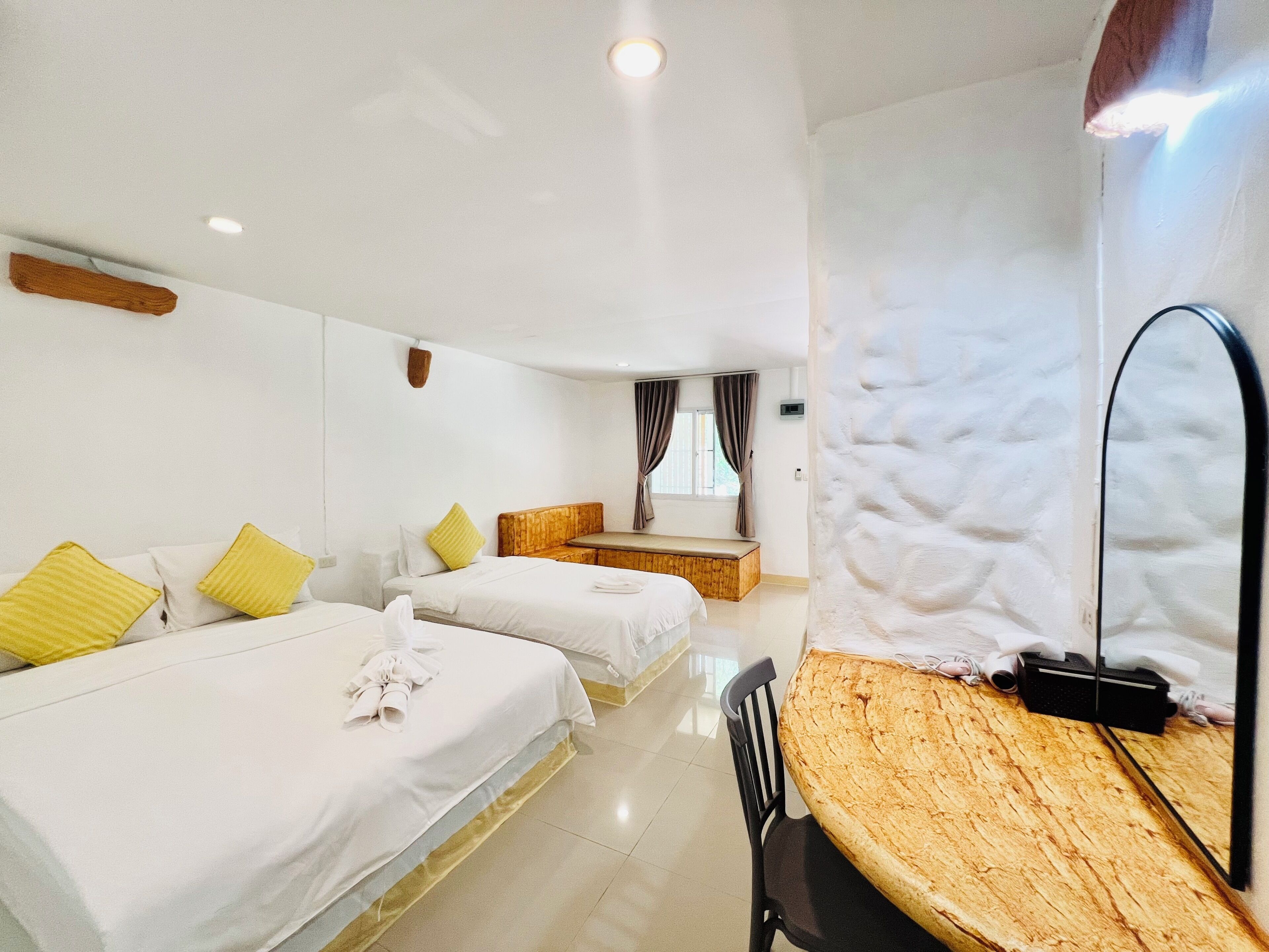 A hotel room with two beds, a wooden dining table, a mirror, and a view of the room's interior.