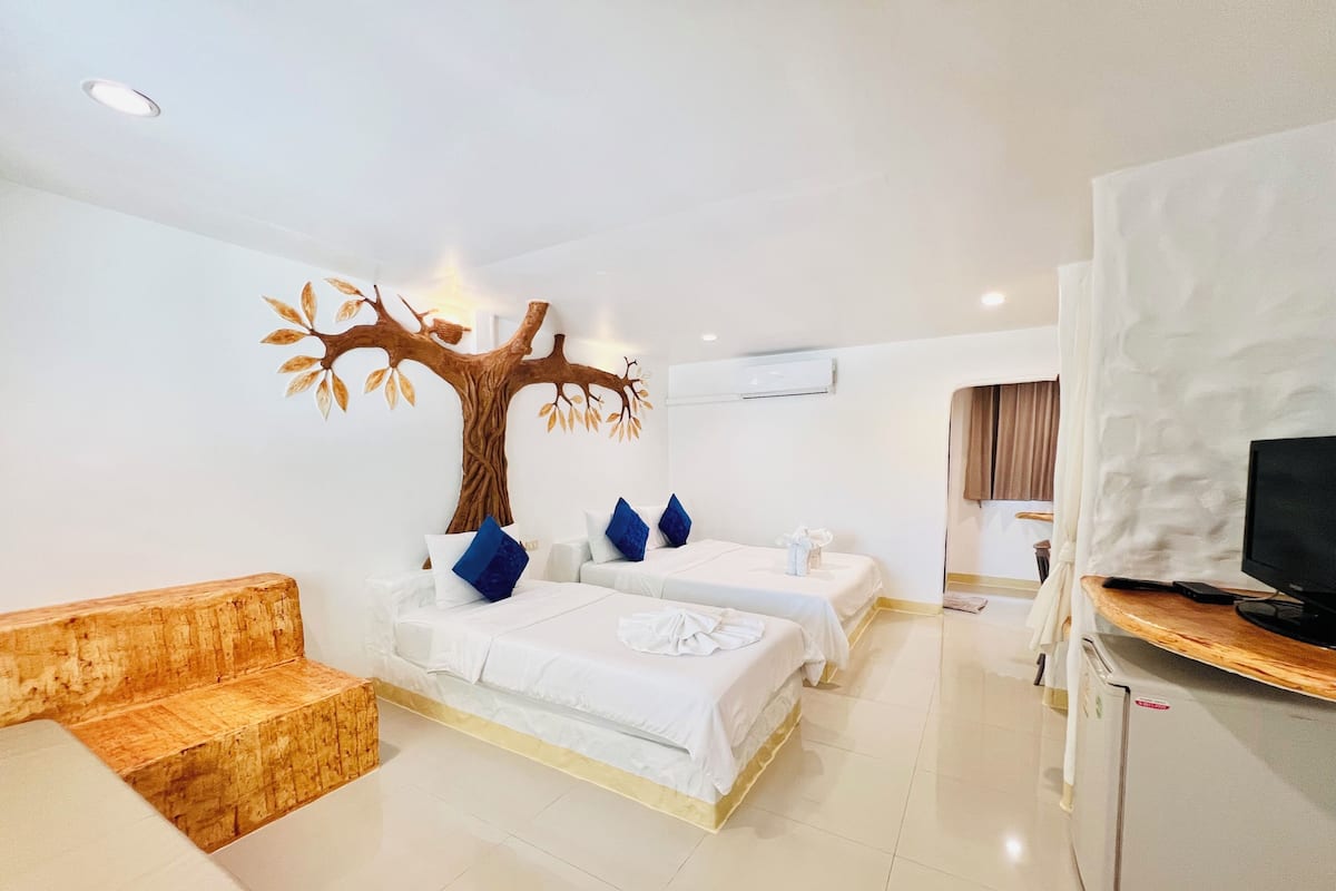 Een hotelkamer met twee bedden, een houten bankje, een televisie en een airconditioning.
