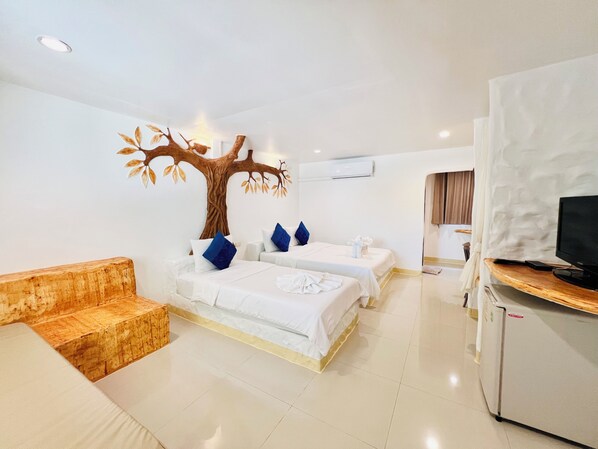 Quarto de hotel com duas camas, um banco de madeira, uma TV e um ar condicionado.