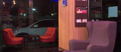 A modern interior with a wooden accent wall, a clock, two red chairs, and a purple armchair.