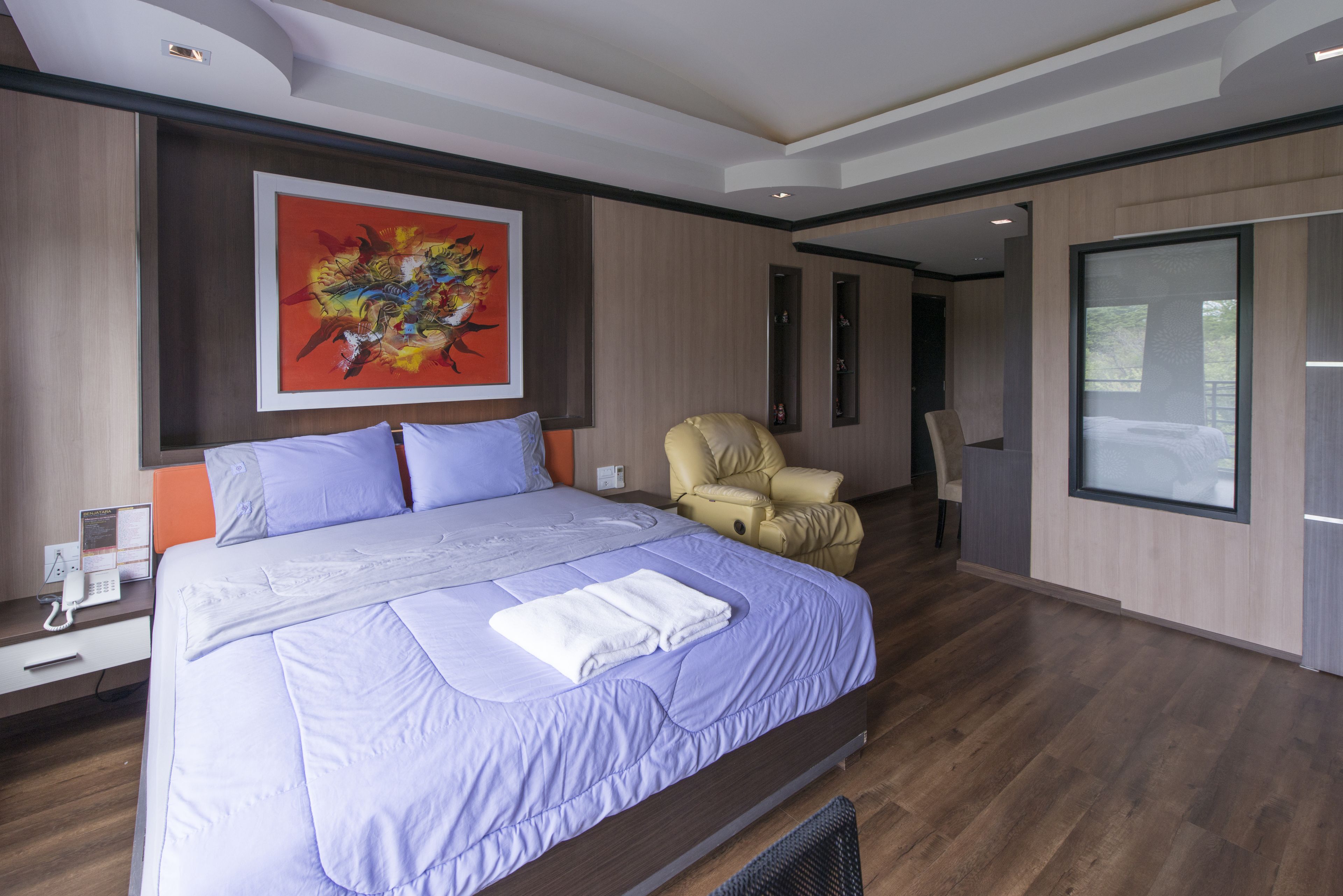 A modern bedroom with a large bed, a massage chair, and a large window.