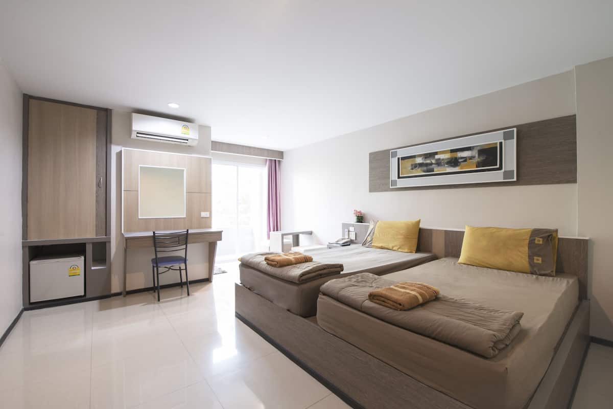 Una habitación de hotel moderna con dos camas, un escritorio, una silla y una pequeña cocina.