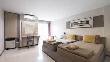 Una habitación de hotel moderna con dos camas, un escritorio, una silla y una pequeña cocina.
