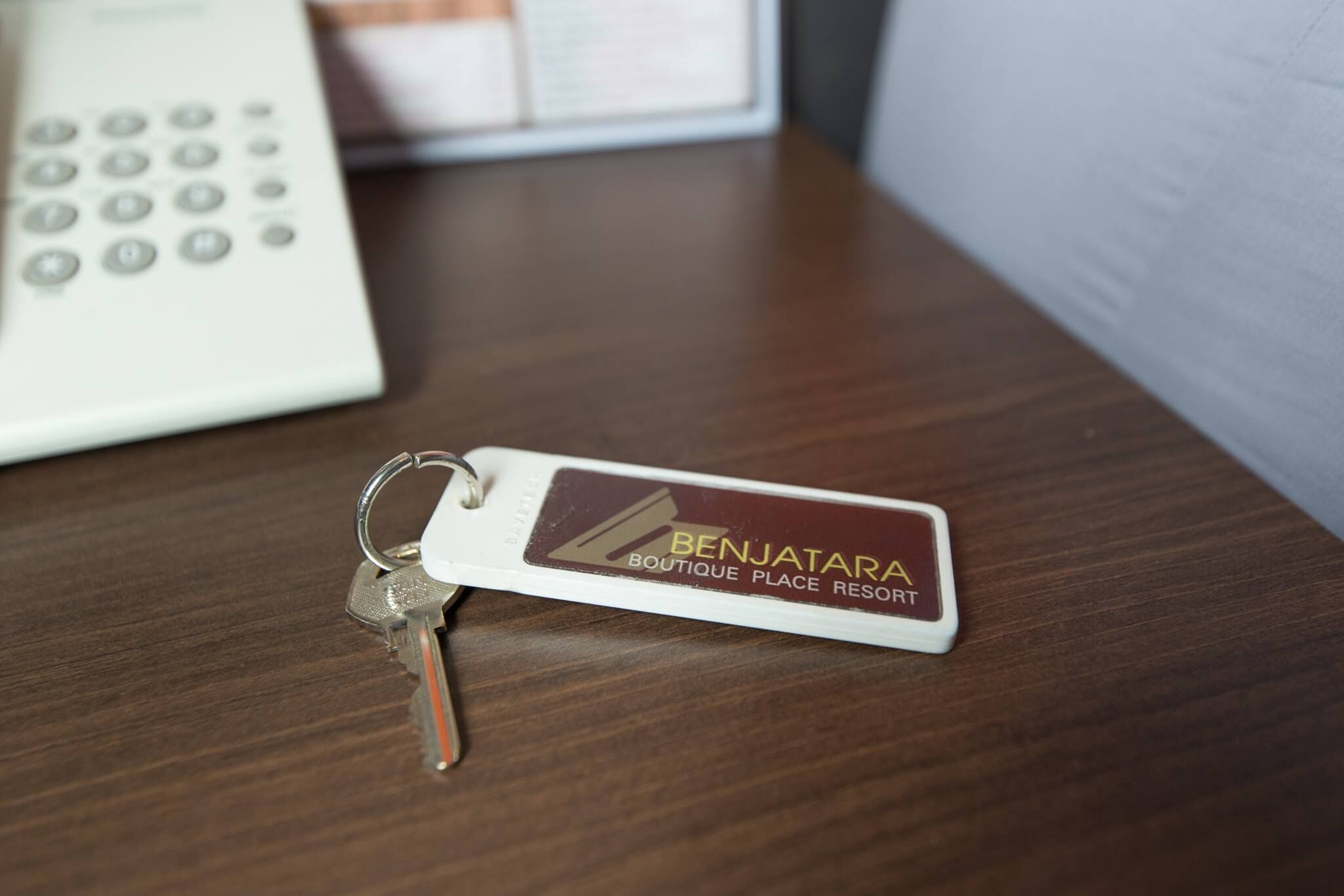 Een sleutelhanger met de tekst 'BENJATARA BOUTIQUE PLACE RESORT' op een houten ondergrond.