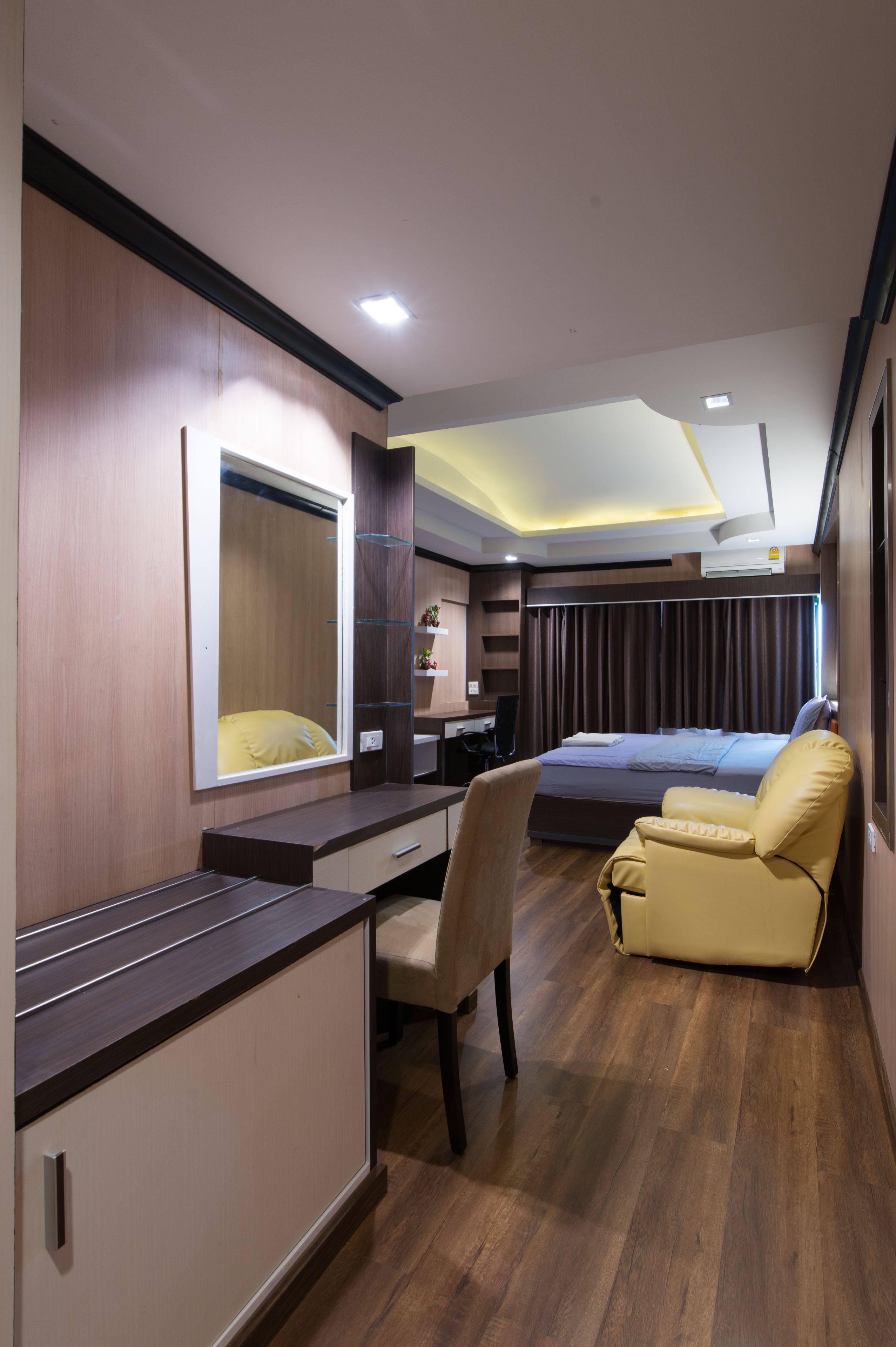 A hotel room with a bed, a desk, a chair, and a large mirror.