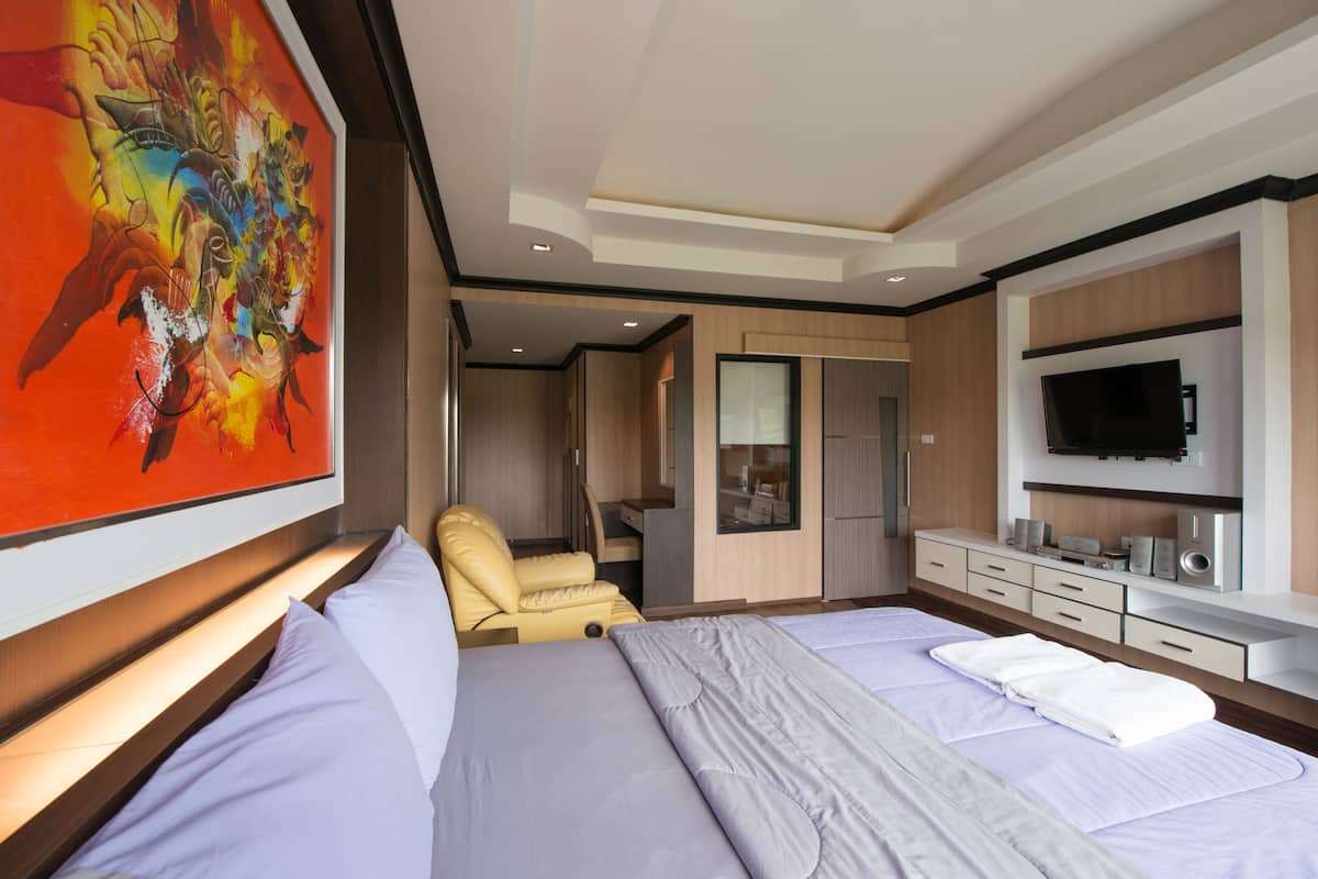 Una habitación de hotel moderna con una cama grande, una zona de estar, un televisor y un cuadro en la pared.