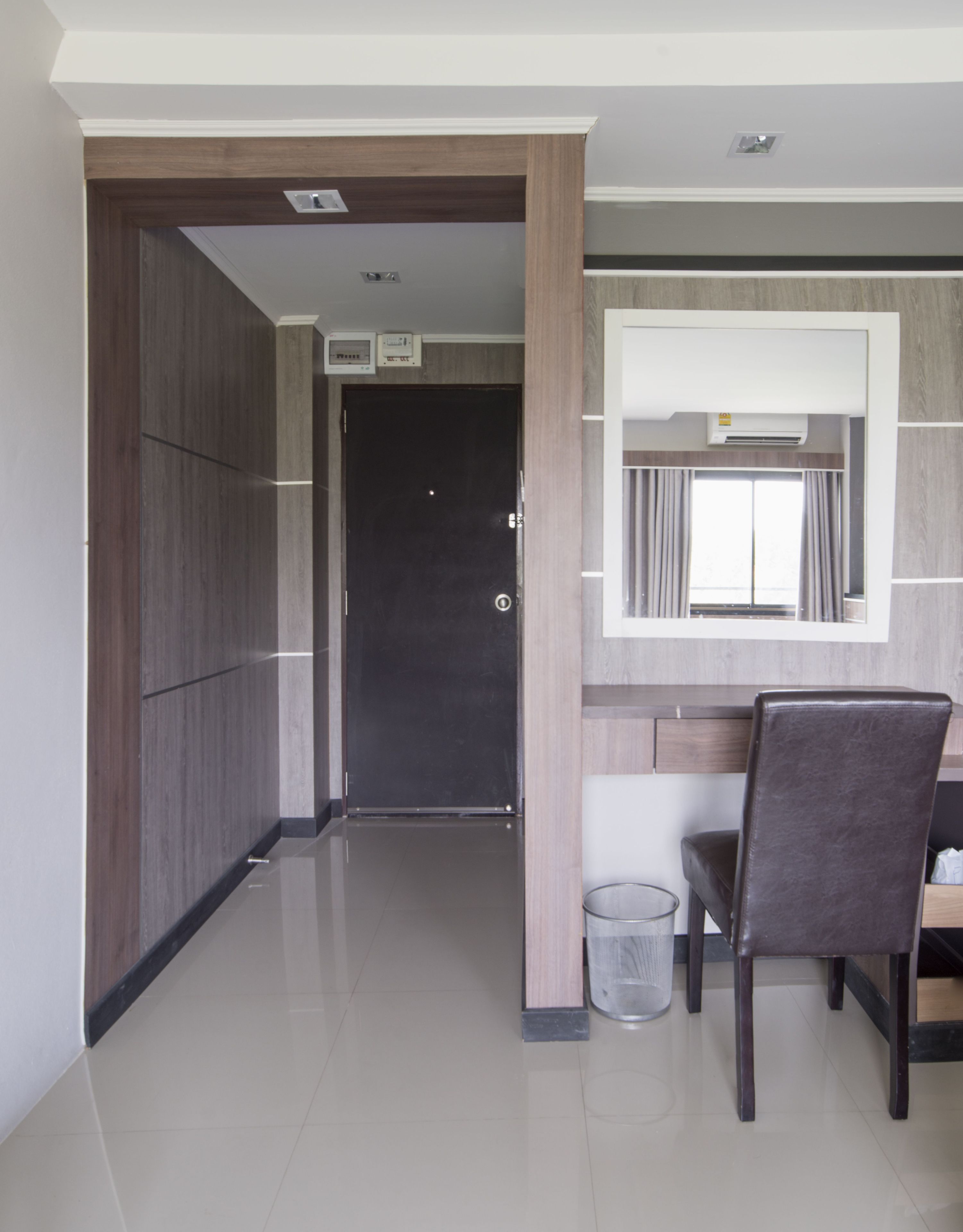 A modern interior with a dark door, a small trash bin, and a dining area with a chair.