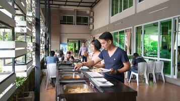 A buffet area with multiple serving stations and white plastic chairs.
