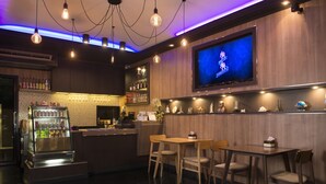 Zona de bar con pantalla de televisión, mostrador, asientos y refrigerador.