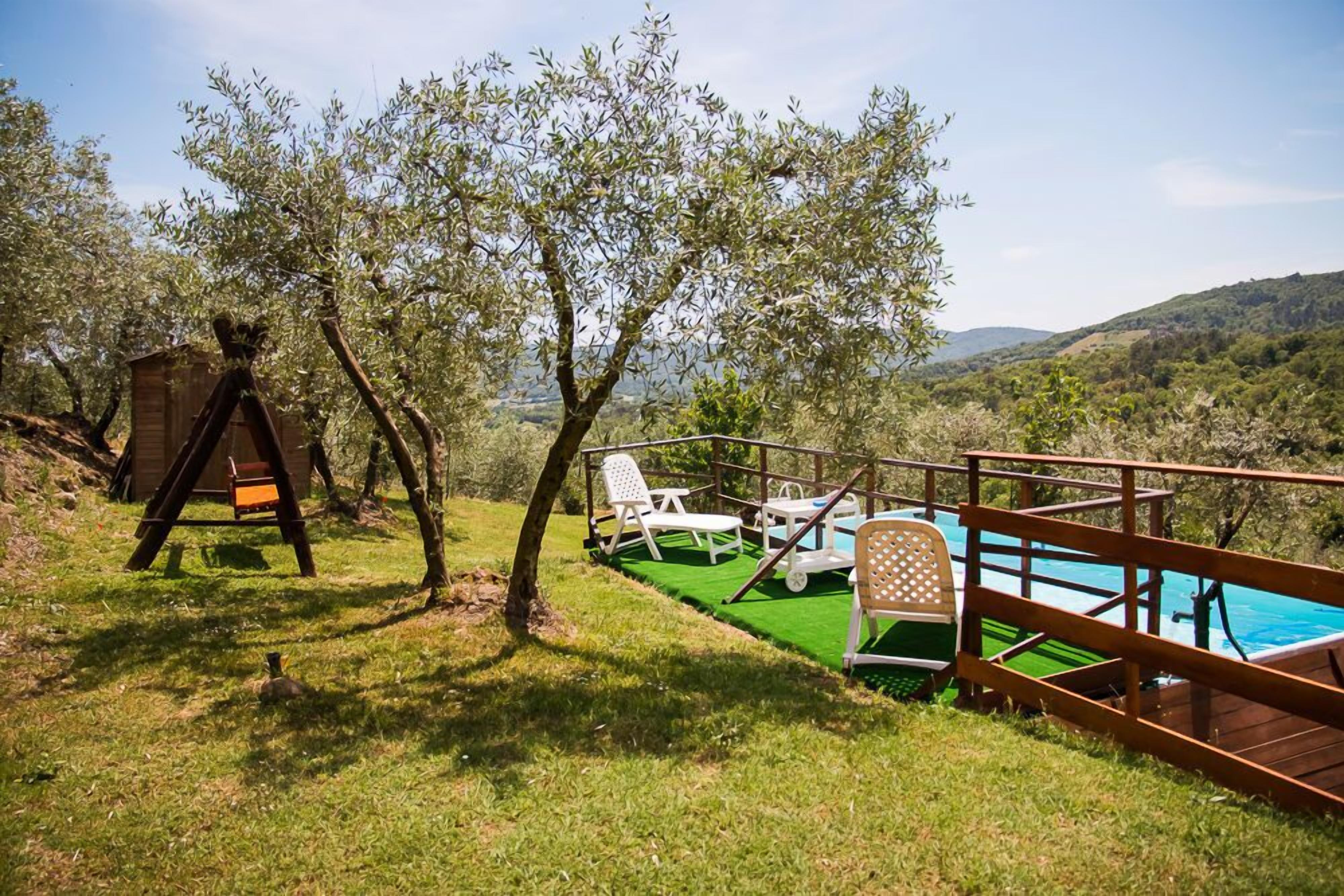 Un espace aménagé au bord de la piscine, avec une terrasse en bois, une petite structure en bois et plusieurs chaises longues blanches.