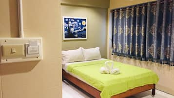 Una habitación de hotel con una cama, un cuadro en la pared y una cortina.