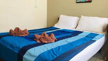 A hotel room with a bed, two pillows, a blue and white striped bedspread, and two brown towels.
