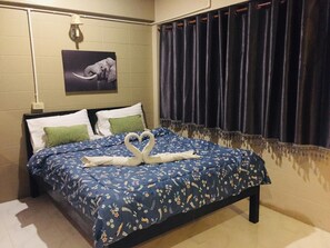 Habitación de hotel con una cama y un edredón de flores azules, además de un arreglo de toallas con forma de cisne.