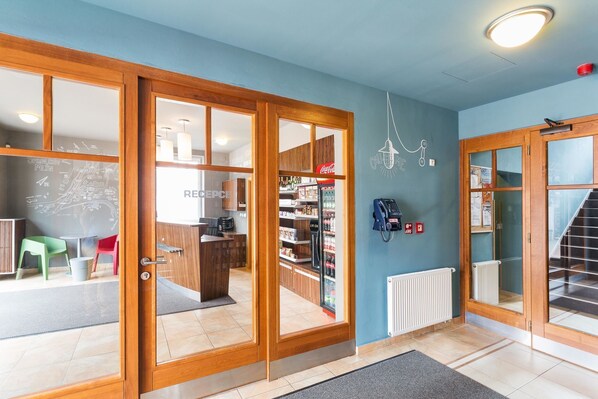 A reception area with a Coca-Cola fridge, a phone, and a map on the wall. - Hotel Grand (Spindleruv mlyn)