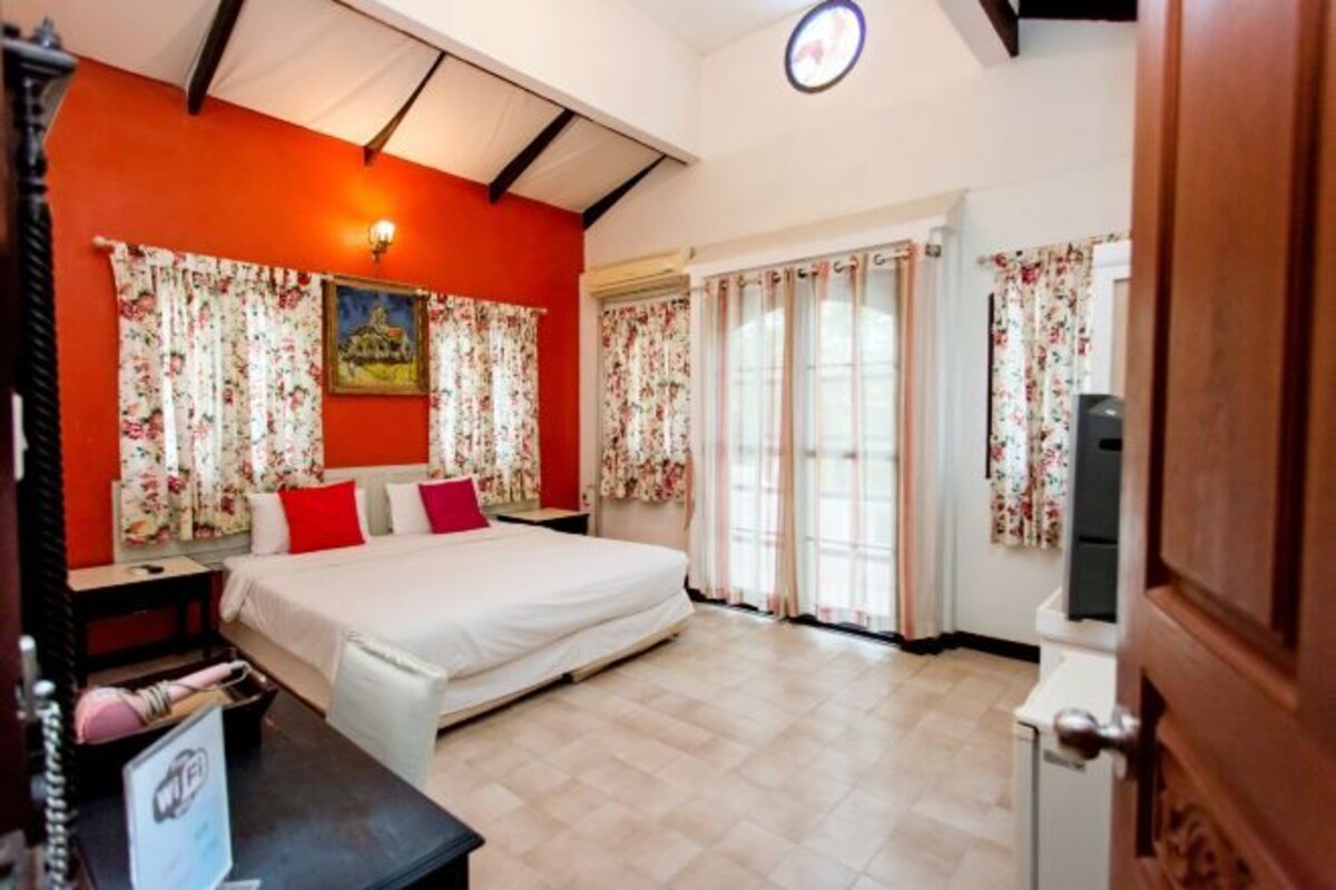 A bedroom with a bed, a nightstand, a desk, and a chair.