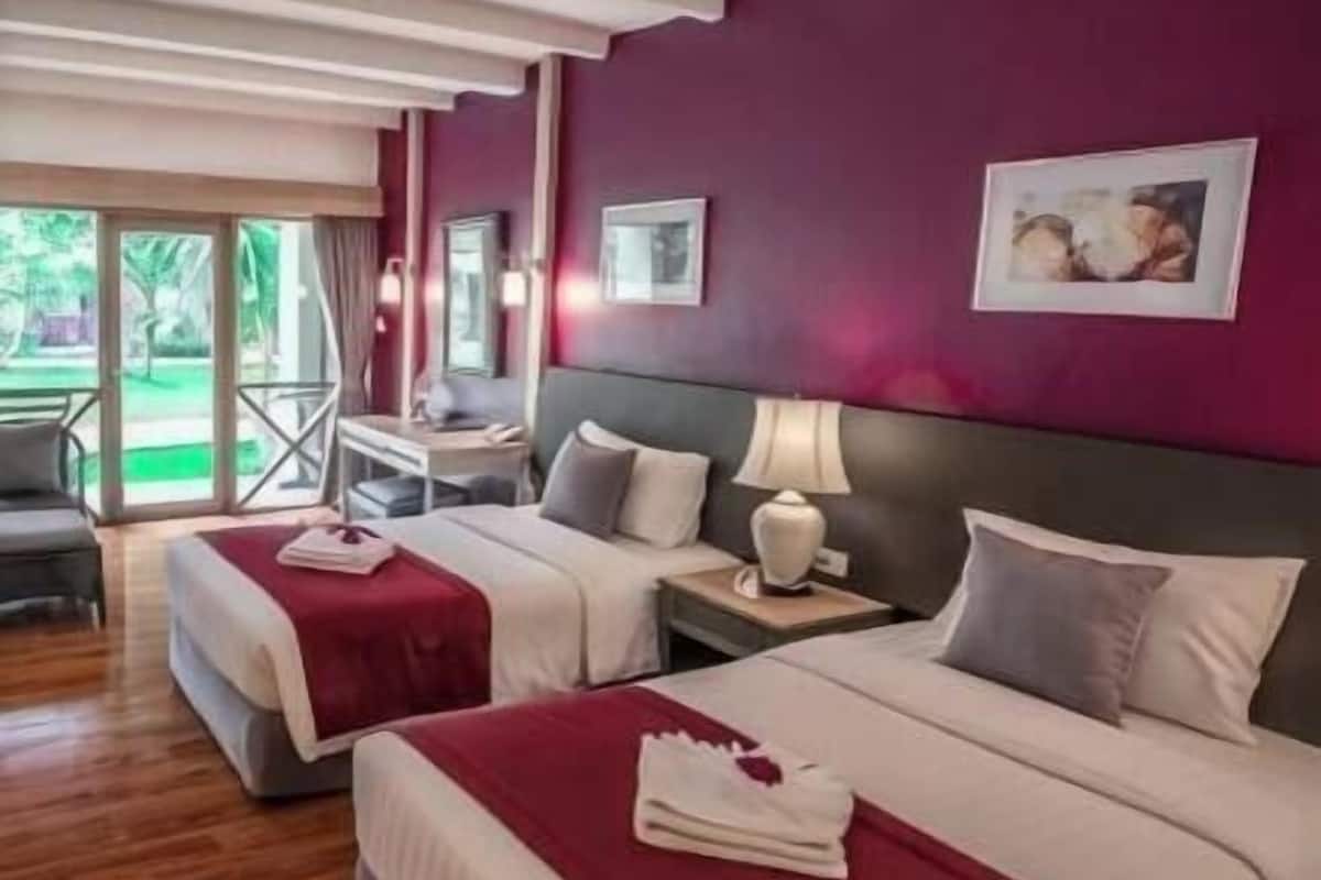 A hotel room with two beds, a desk, and a view of the outdoors.
