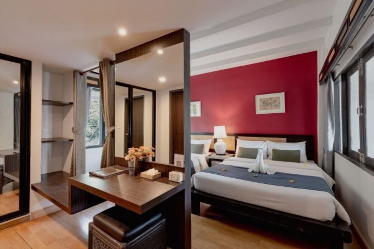 A hotel room with a bed, bedside table, and a large mirror.