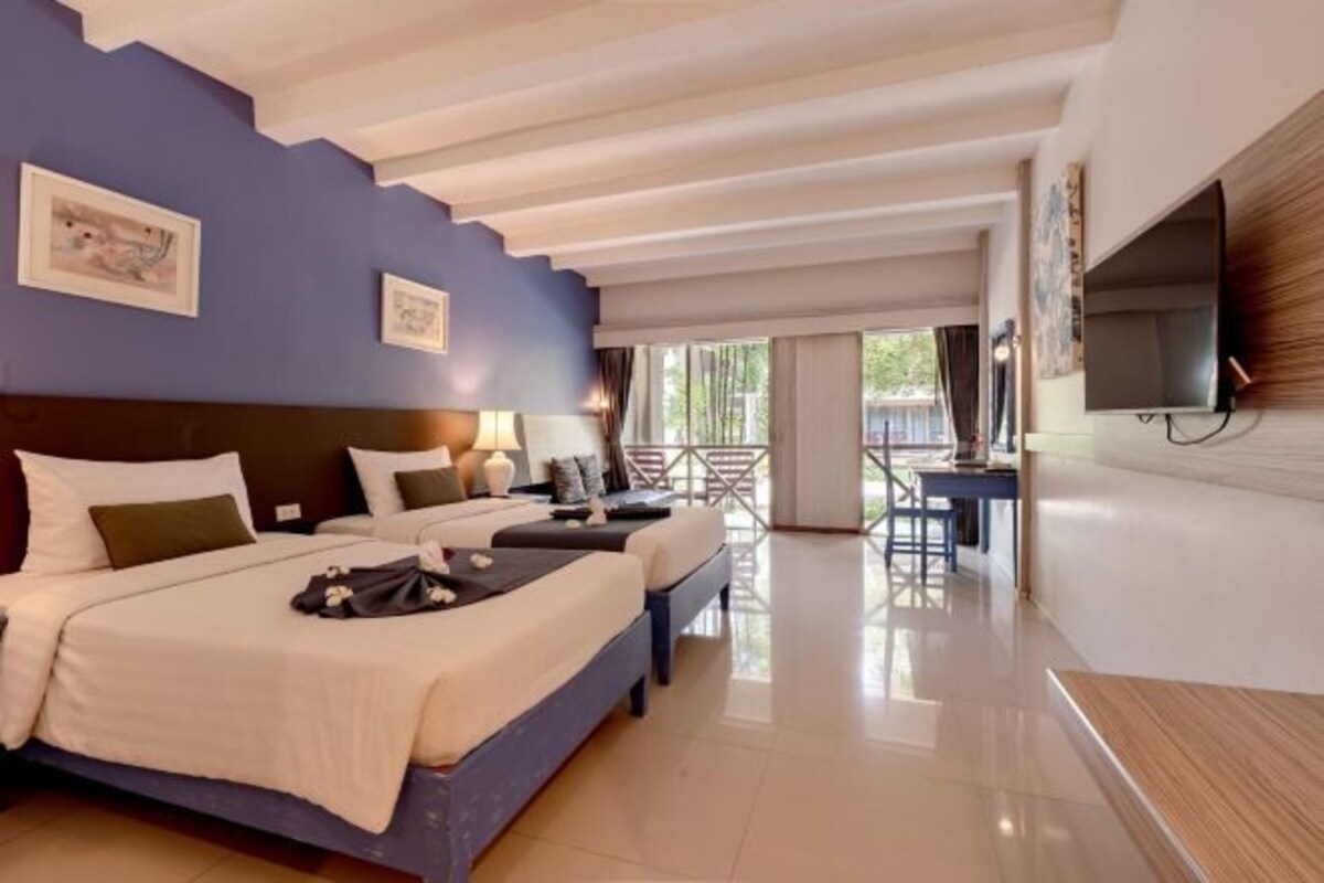 A hotel room with a bed, bedside tables, a desk, and a TV.