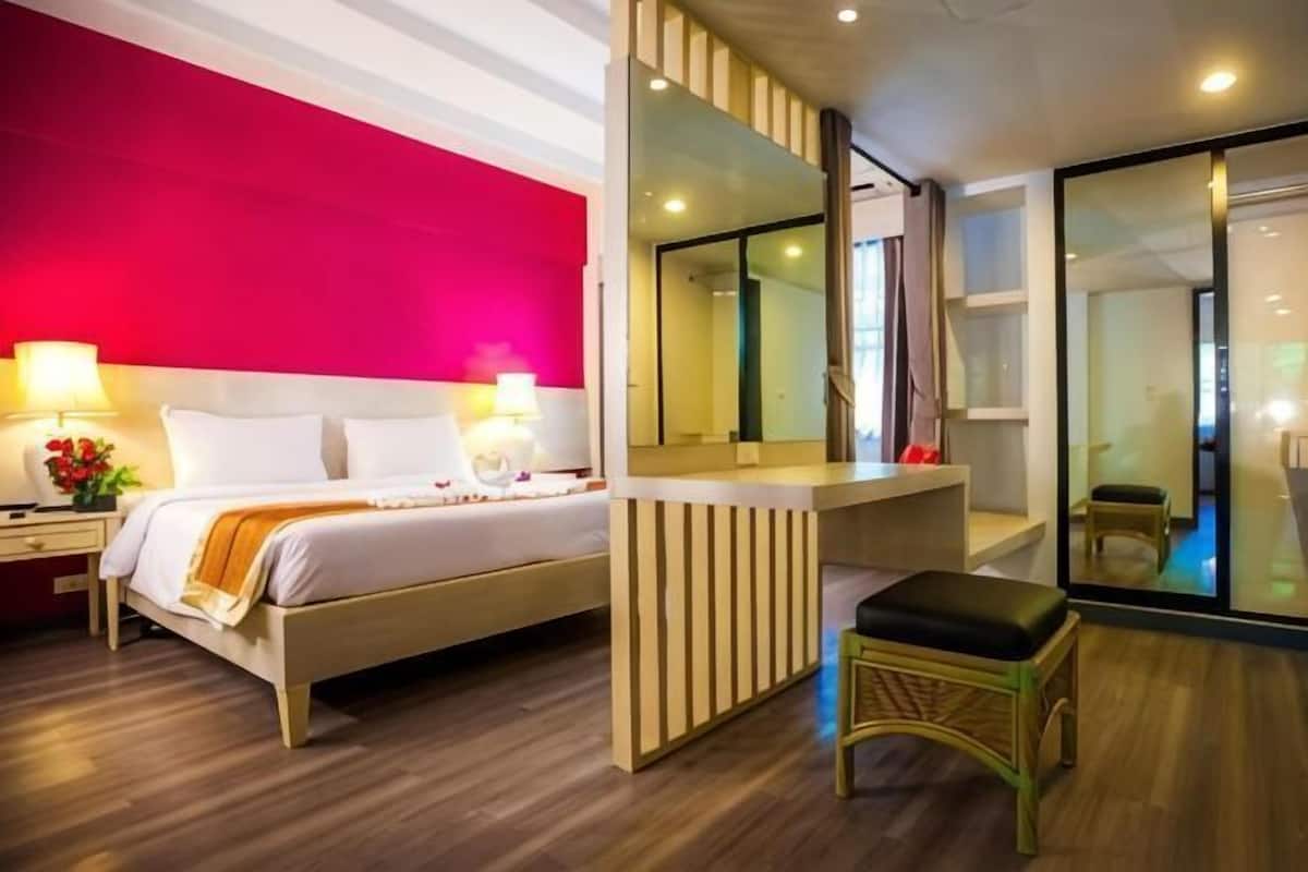 A modern hotel room with a bed, bedside table, lamp, and a large mirror.