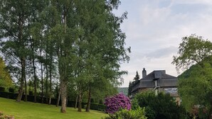 A garden with a stone bench, a lantern, and a variety of flowers. - Auberge d'Alle (Vresse-sur-Semois)