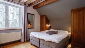 A bedroom with a bed, wooden beams, a radiator, a window with curtains, and a mirror. - Auberge d'Alle (Vresse-sur-Semois)
