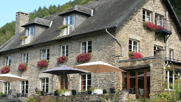 A stone building with multiple windows, outdoor seating with umbrellas, and flower boxes. - Auberge d'Alle (Vresse-sur-Semois)
