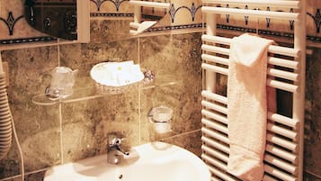 Un baño con lavamanos, perchero para toallas y azulejos decorativos.
