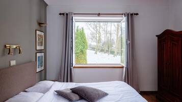 Quarto com cama, janela com cortinas, guarda-roupa e iluminação embutida na parede.