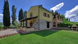 A two-story house with a covered patio and a well-maintained lawn. - Villa Sabrina (San Gimignano)