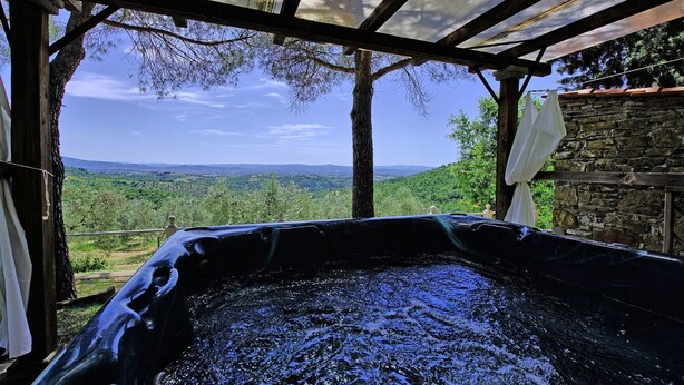 A hot tub under a wooden pergola with a view of a green landscape. - Villa Luciano (Arezzo)