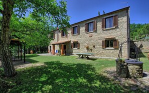 Ein Steinhaus mit Terrasse, einem Tisch und einem gepflegten Rasen.