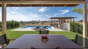 A covered outdoor area with a pool, lounge chairs, and a table with a decorative centerpiece. - Esperanza Villas (Nea Propontida)