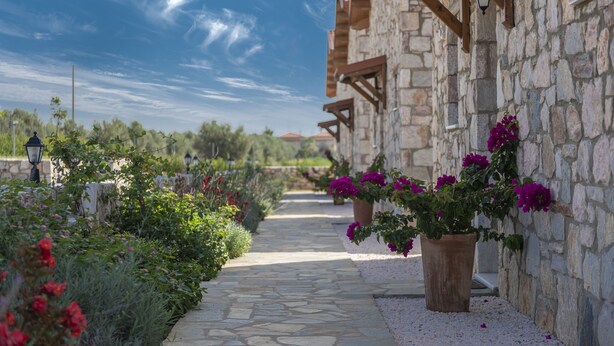 A stone pathway leading to a building with wooden beams and a stone wall. - Esperanza Villas (Nea Propontida)