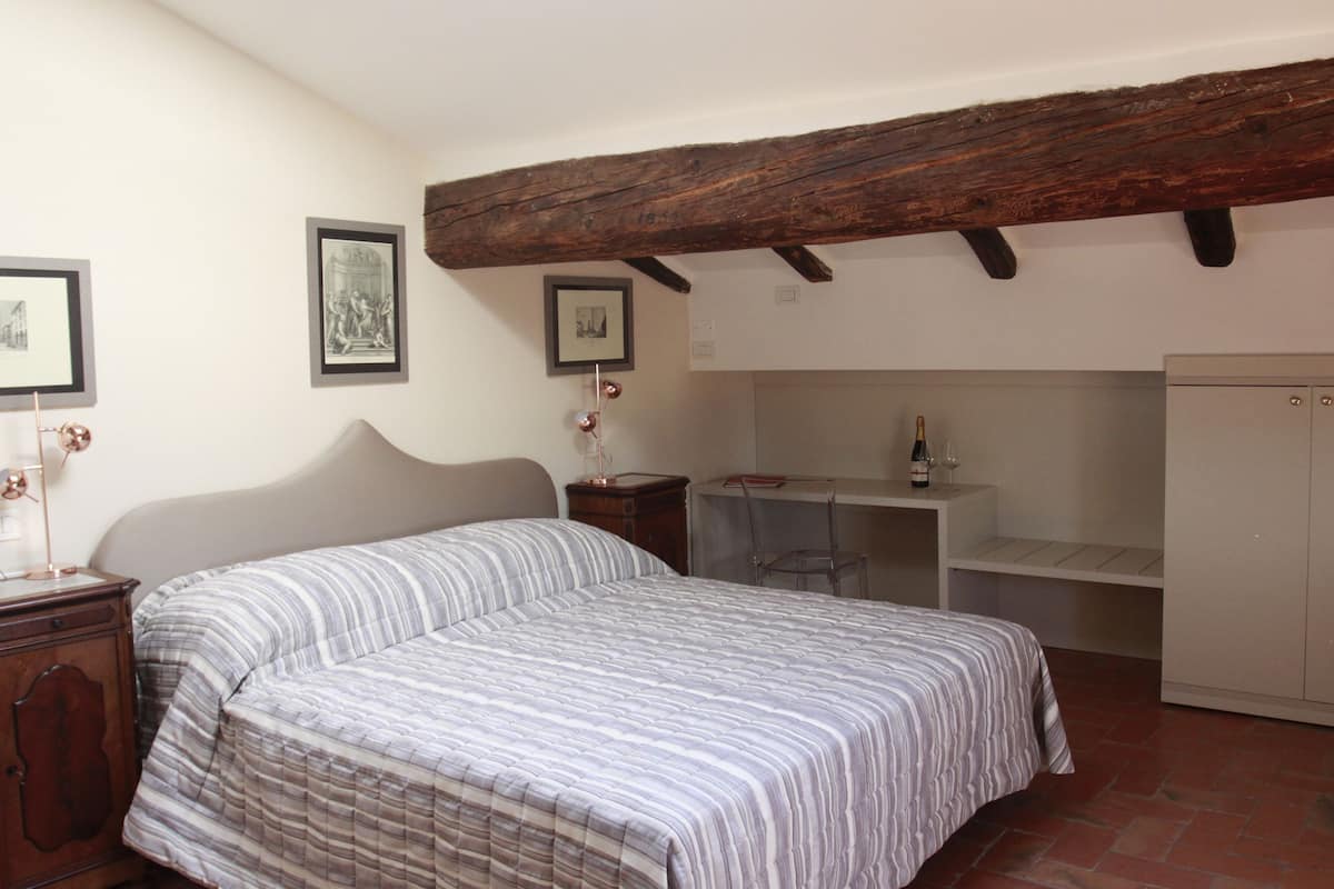 A bedroom with a bed, a desk, and a wardrobe.