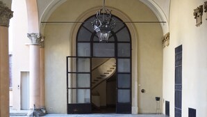 An arched doorway with a chandelier, a staircase, and a column. - Casa Isolani Santo Stefano (Bologna)