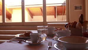 A breakfast table with cups, a glass of water, and a bowl of food. - Casa Isolani Santo Stefano (Bologna)