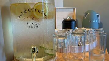 Un recipiente grande de vidrio para ponche con el rótulo 'Palm Cocktail', diseño vintage, sobre una mesa de madera.
