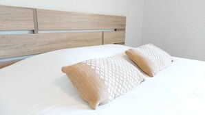 Un lit avec une tête de lit en bois et deux coussins à motifs.
