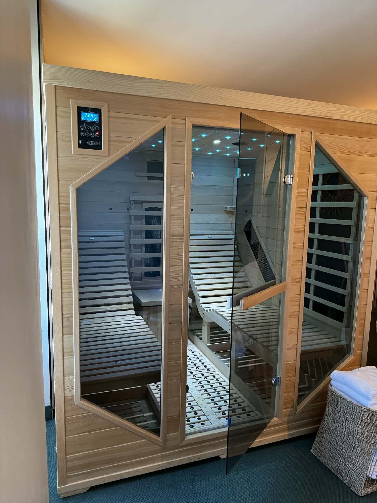 A sauna with a wooden exterior, glass doors, and a control panel.