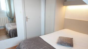 A bedroom with a bed, a bedside table, a lamp, and a mirror.